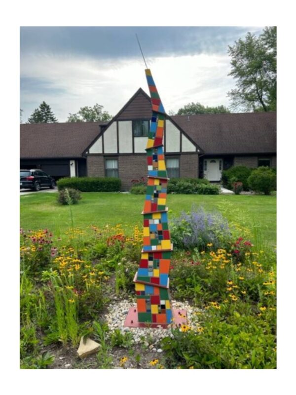Colorful abstract sculpture in a garden setting.