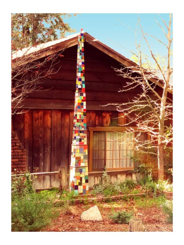 Wooden cabin with colorful sculpture outside.